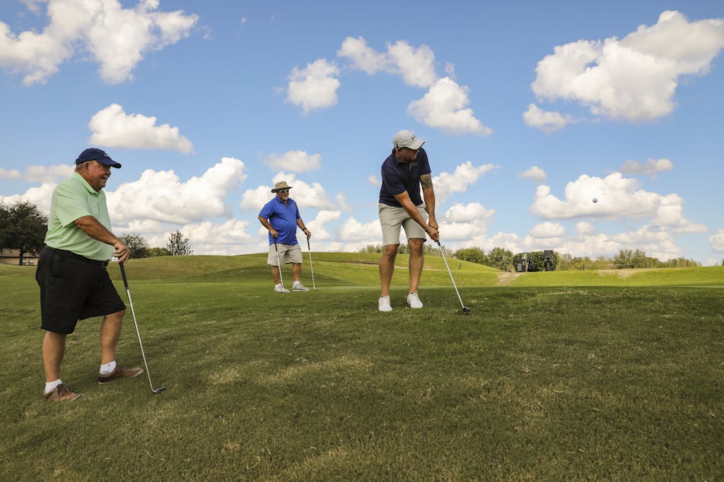 Three men enjoy a sunny round of golf on a vibrant green course in Florida.